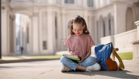 Foto de Alumno de primaria. Chica con mochilas al aire libre. Comienzo de las lecciones. Primer día de otoño. - Imagen libre de derechos