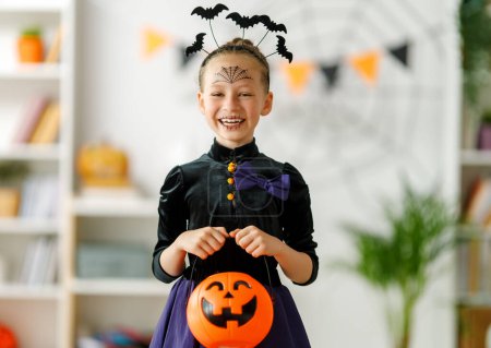 Foto de Lindo niño pequeño con cesta de calabaza. Chica feliz preparándose para Halloween. Chico gracioso en casa. - Imagen libre de derechos