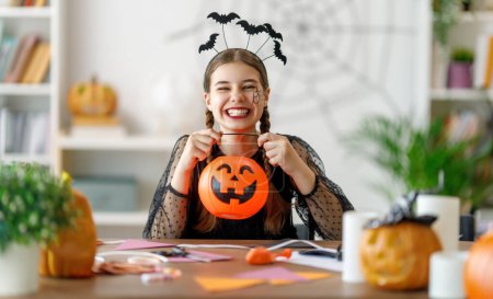 Foto de Adolescente linda con calabaza tallada. Chica feliz preparándose para Halloween. Chico gracioso en casa. - Imagen libre de derechos