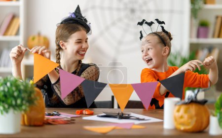 Photo for Happy family preparing for Halloween. Cute children in carnival costumes carving pumpkins at home. - Royalty Free Image
