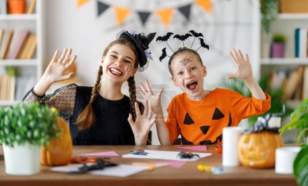 Téléchargez les photos : Bonne famille se préparant pour Halloween. Enfants mignons en costumes de carnaval sculptant citrouilles à la maison. - en image libre de droit