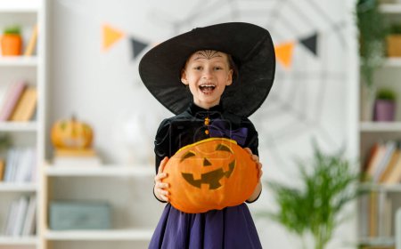 Foto de Lindo niño pequeño con cesta de calabaza. Chica feliz preparándose para Halloween. Chico gracioso en casa. - Imagen libre de derechos
