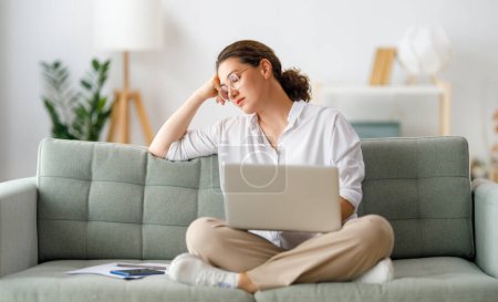 Téléchargez les photos : Femme fatiguée de travailler en ligne, regarder webinaire, podcast sur ordinateur portable, prendre des notes. - en image libre de droit