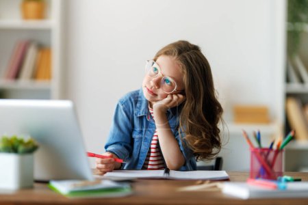 Foto de De vuelta a la escuela. El niño feliz está sentado en el escritorio. Chica haciendo deberes o educación en línea. - Imagen libre de derechos