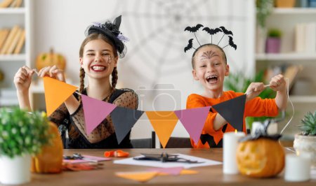 Foto de Familia feliz preparándose para Halloween. Lindos niños en trajes de carnaval tallando calabazas en casa. - Imagen libre de derechos