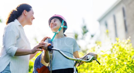Photo for Girl  in safety helmet with bike and backpack. Happy child with mother. Safe way for kids to school - Royalty Free Image