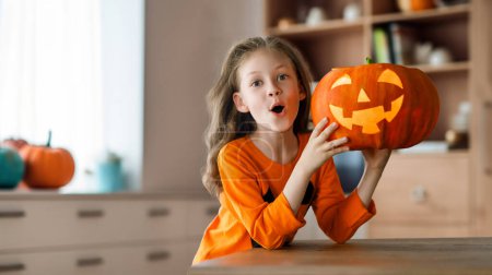 Téléchargez les photos : Petite fille mignonne avec citrouille sculptée. Bonne famille se préparant pour Halloween. - en image libre de droit