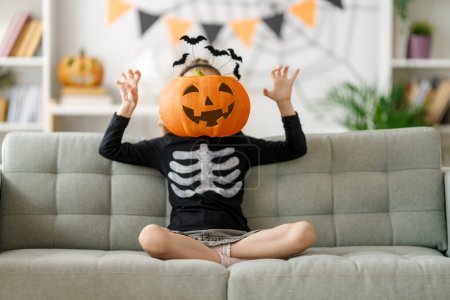 Foto de Lindo niño con calabaza tallada. Chica feliz preparándose para Halloween. Chico gracioso en casa. - Imagen libre de derechos