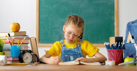 Photo for Back to school. Thinking child is sitting at desk. Girl doing homework. - Royalty Free Image