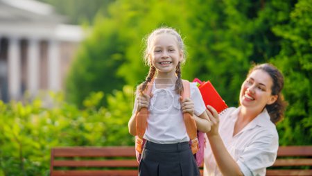 Photo for Parent and kid going to school. Woman and girl with backpack behind the back. Beginning of lessons. - Royalty Free Image