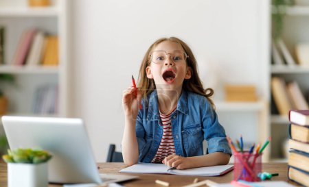 Foto de De vuelta a la escuela. El niño feliz está sentado en el escritorio. Chica haciendo deberes o educación en línea. - Imagen libre de derechos