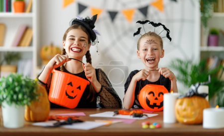 Photo for Happy family preparing for Halloween. Cute children in carnival costumes carving pumpkins at home. - Royalty Free Image