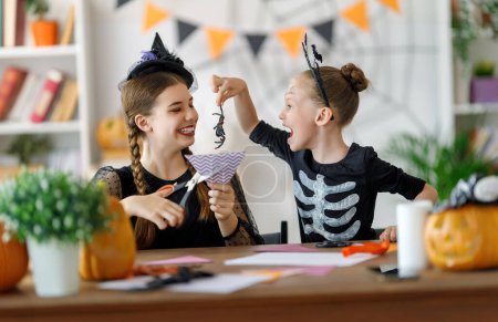 Téléchargez les photos : Bonne famille se préparant pour Halloween. Enfants mignons en costumes de carnaval sculptant citrouilles à la maison. - en image libre de droit