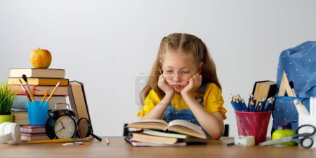 Photo for Back to school. Thinking child is sitting at desk. Girl doing homework. - Royalty Free Image