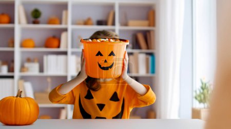 Téléchargez les photos : Petite fille mignonne avec panier à citrouille. Bonne famille se préparant pour Halloween. - en image libre de droit
