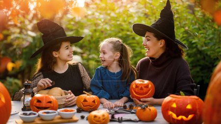 Foto de Familia feliz preparándose para Halloween. Madre e hijos tallando calabazas en el patio trasero de la casa. - Imagen libre de derechos