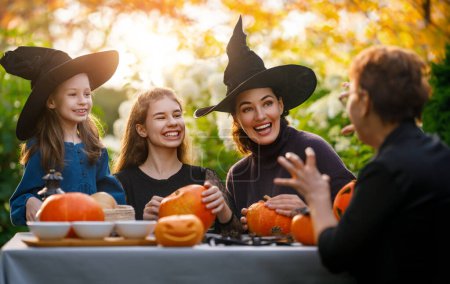 Photo for Happy family preparing for Halloween. Mother, grandmother and children carving pumpkins in the backyard of the house. - Royalty Free Image