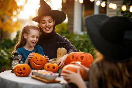 Photo for Happy family preparing for Halloween. Mother and children carving pumpkins in the backyard of the house. - Royalty Free Image