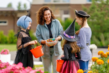 Foto de Gente feliz celebrando Halloween. Adulto está tratando con dulces niños al aire libre. - Imagen libre de derechos