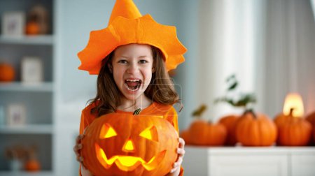 Téléchargez les photos : Petite fille mignonne avec citrouille sculptée. Bonne famille se préparant pour Halloween. - en image libre de droit