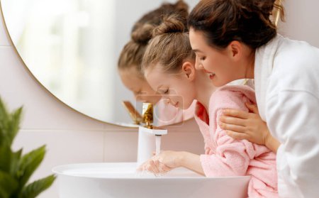 Photo for Cute little girl and her mother are washing hands under running water. - Royalty Free Image