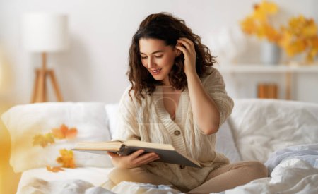 Photo for Portrait of young woman enjoying reading book at home. - Royalty Free Image