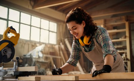 Photo for Young woman carpenter is working in a workshop. - Royalty Free Image