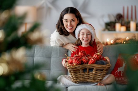 Téléchargez les photos : Joyeux Noël, Joyeuses Fêtes. Maman et fille près de l'arbre à l'intérieur. Le matin avant Noël. - en image libre de droit