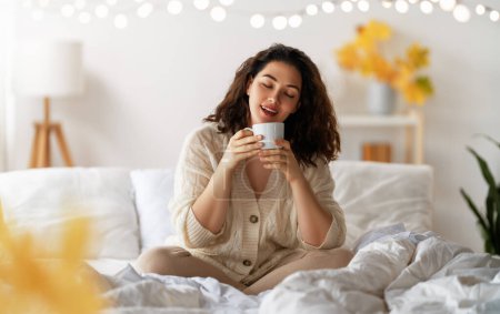 Téléchargez les photos : Joyeux jeune femme profitant matin ensoleillé sur le lit. - en image libre de droit