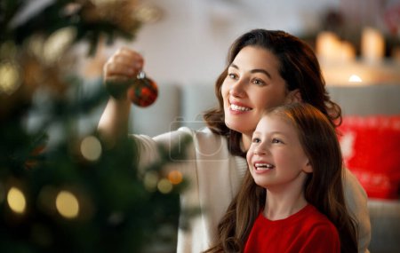 Foto de Feliz Navidad, Felices Fiestas. Mamá e hija cerca del árbol en el interior. La mañana antes de Navidad. - Imagen libre de derechos