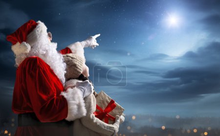 Téléchargez les photos : Joyeux Noël et bonnes vacances. Petite fille mignonne et Père Noël avec un cadeau. Concept légende de Noël. - en image libre de droit