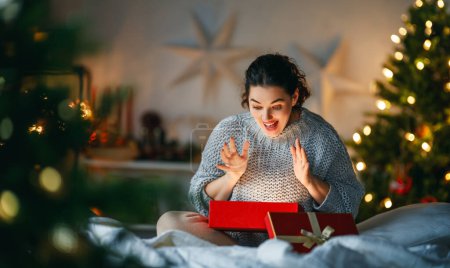 Téléchargez les photos : Joyeux Noël, Joyeuses Fêtes. Surprise femme heureuse ouvrant un cadeau de Noël. - en image libre de droit