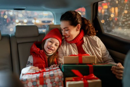 Foto de Mujer y su hijo sosteniendo regalos y entregándolos en coche a casa. Concepto de vacaciones. Tiempo de Nochebuena. - Imagen libre de derechos