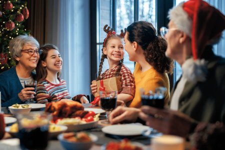 Photo for Merry Christmas! Happy family are having dinner at home. Celebration holiday and togetherness near tree. - Royalty Free Image