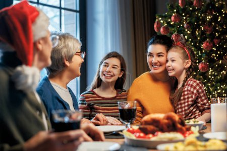 Foto de ¡Feliz Navidad! La familia feliz cenará en casa. Fiesta de celebración y unión cerca del árbol. - Imagen libre de derechos