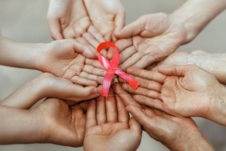 Photo for Hands of women with pink satin ribbon symbolizing concept of illness awareness, expressing solidarity and support for cancer patients and survivors. Different generations of people - Royalty Free Image