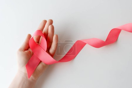 Photo for Hands of woman with pink satin ribbon symbolizing concept of illness awareness, expressing solidarity and support for cancer patients and survivors. Different generations of people - Royalty Free Image