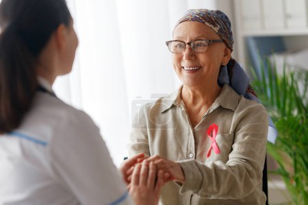Photo for Pink ribbon for breast cancer awareness. Female patient listening to doctor in medical office. Support people living with tumor illness. - Royalty Free Image