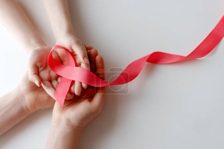 Foto de Las manos de las mujeres con cinta de satén rosa simbolizan el concepto de conciencia de la enfermedad, expresando solidaridad y apoyo a los pacientes y sobrevivientes de cáncer. Diferentes generaciones de personas - Imagen libre de derechos