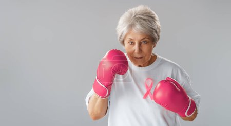 Téléchargez les photos : Femme en gants de boxe avec un ruban rose comme symbole de la lutte contre le cancer. Accroître le niveau de connaissances sur les personnes qui ont surmonté les maladies tumorales. - en image libre de droit