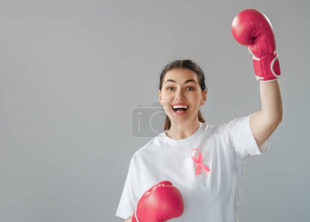 Téléchargez les photos : Femme en gants de boxe avec un ruban rose comme symbole de la lutte contre le cancer. Accroître le niveau de connaissances sur les personnes qui ont surmonté les maladies tumorales. - en image libre de droit