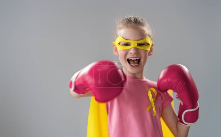Téléchargez les photos : Enfant en gants de boxe avec un ruban jaune comme symbole de la lutte contre le cancer. Accroître le niveau de connaissances sur les enfants qui ont surmonté les maladies tumorales. - en image libre de droit