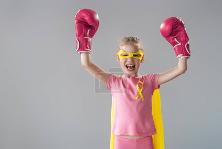 Téléchargez les photos : Enfant en gants de boxe avec un ruban jaune comme symbole de la lutte contre le cancer. Accroître le niveau de connaissances sur les enfants qui ont surmonté les maladies tumorales. - en image libre de droit