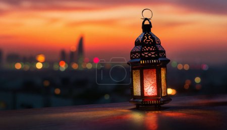 Foto de Linterna árabe ornamental con vela encendida que brilla en el fondo nocturno. Tarjeta de felicitación festiva, invitación para el mes sagrado musulmán Ramadán Kareem. - Imagen libre de derechos