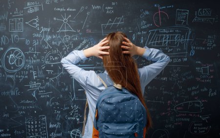 Photo for Back to school. Unhappy teenager indoors. Girl is learning in class on background of blackboard. - Royalty Free Image