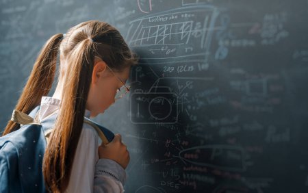 Photo for Back to school. Unhappy kid indoors. Girl is learning in class on background of blackboard. - Royalty Free Image
