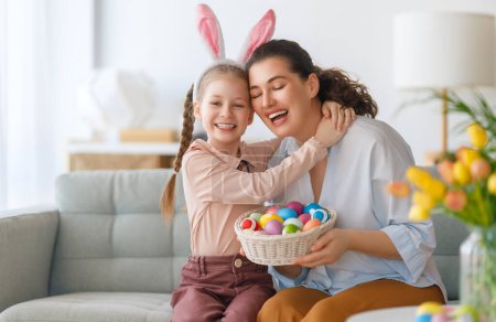 Téléchargez les photos : Joyeuses vacances ! Mère et sa fille peignent des œufs. Famille célébrant Pâques. Petite fille mignonne enfant porte des oreilles de lapin. - en image libre de droit