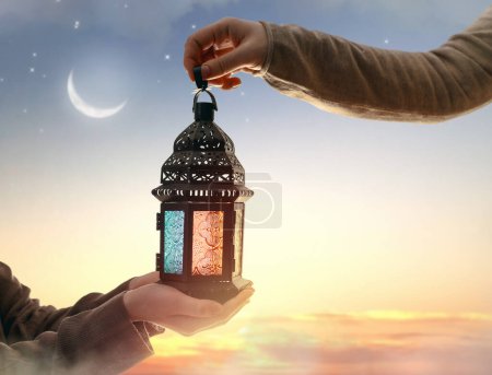 Téléchargez les photos : Lanterne arabe ornementale avec bougie allumée à la main. Carte de vœux festive, invitation pour le mois saint musulman Ramadan Kareem. - en image libre de droit