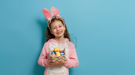 Foto de Lindo niño pequeño con orejas de conejo en el día de Pascua. Chica con huevos pintados. - Imagen libre de derechos