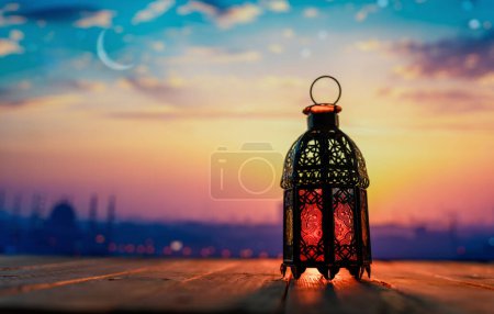 Foto de Linterna árabe ornamental con vela encendida que brilla en el fondo nocturno. Tarjeta de felicitación festiva, invitación para el mes sagrado musulmán Ramadán Kareem. - Imagen libre de derechos